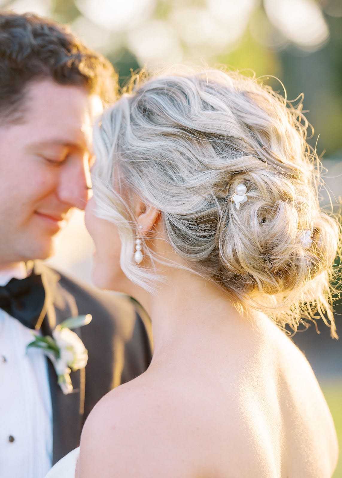 Bride and groom smiling at each other in soft, golden sunlight.