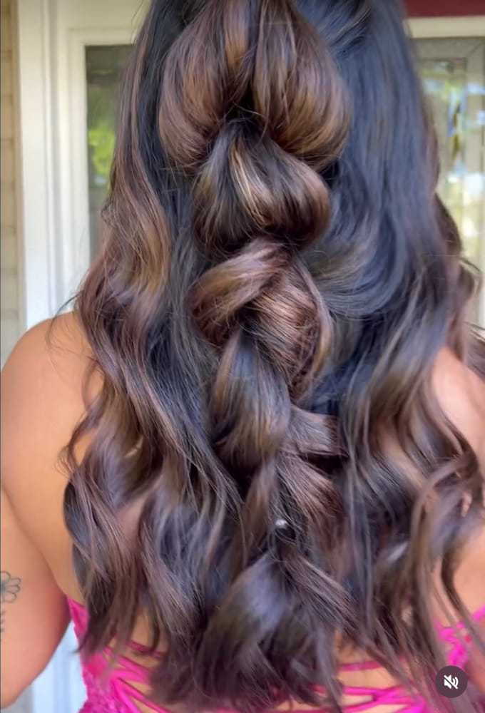 Braided hairstyle with loose curls on dark brown hair.