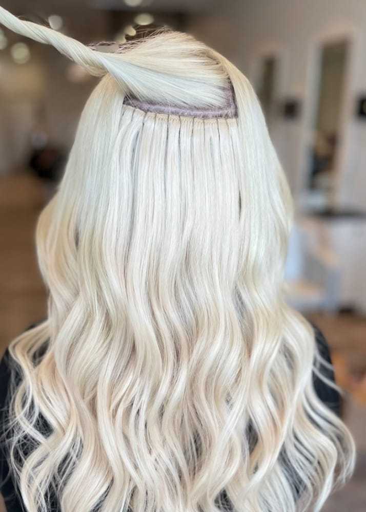 Blonde hair with extensions; focus on weft and styling in a salon setting.